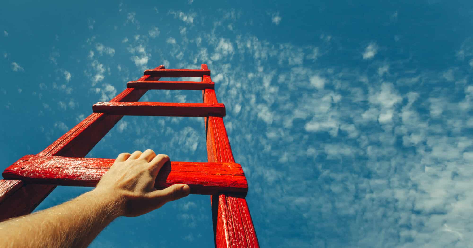A hand on a red ladder pointed toward the sky.
