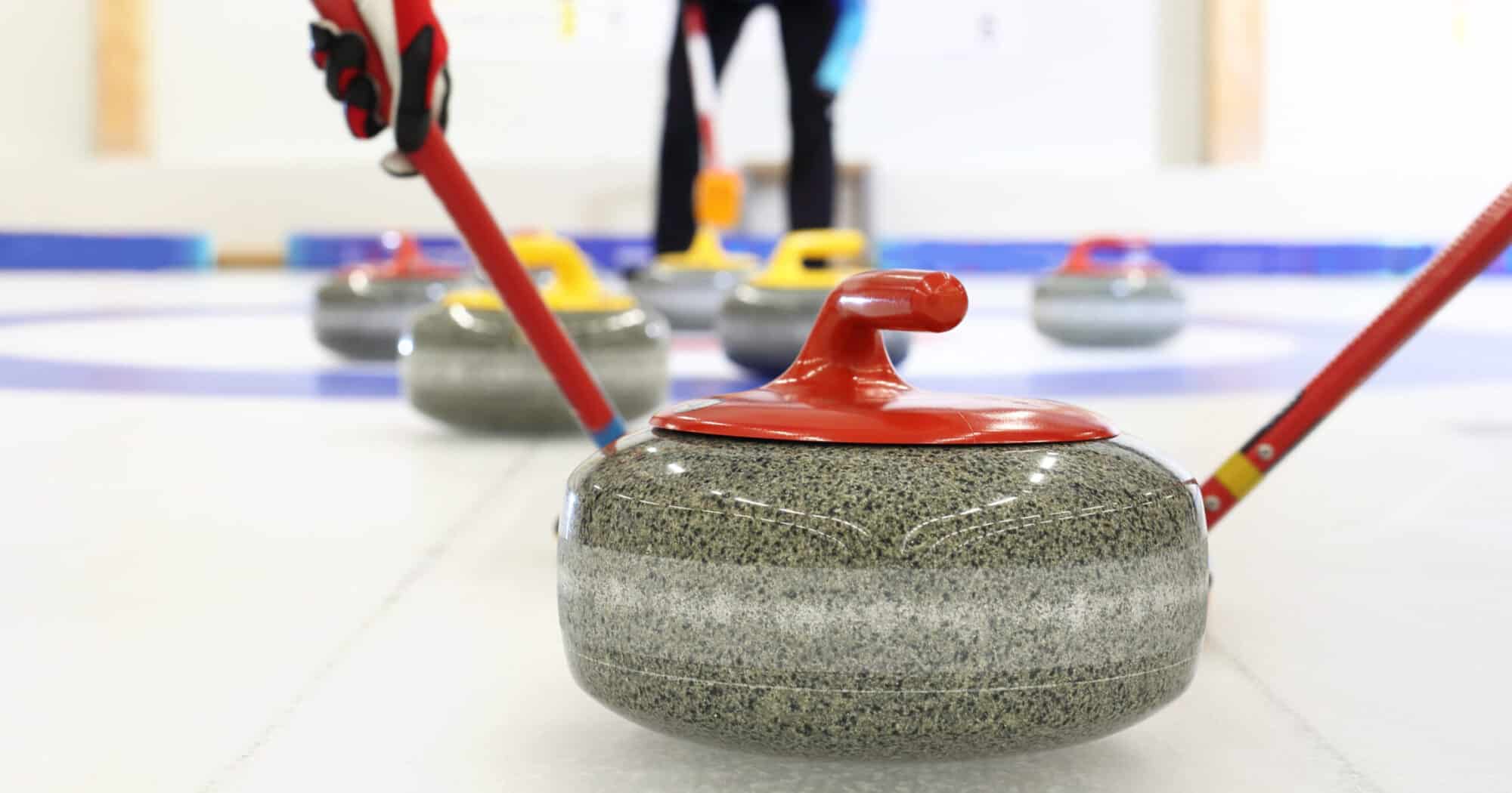A closeup of a curling stone in a rink.